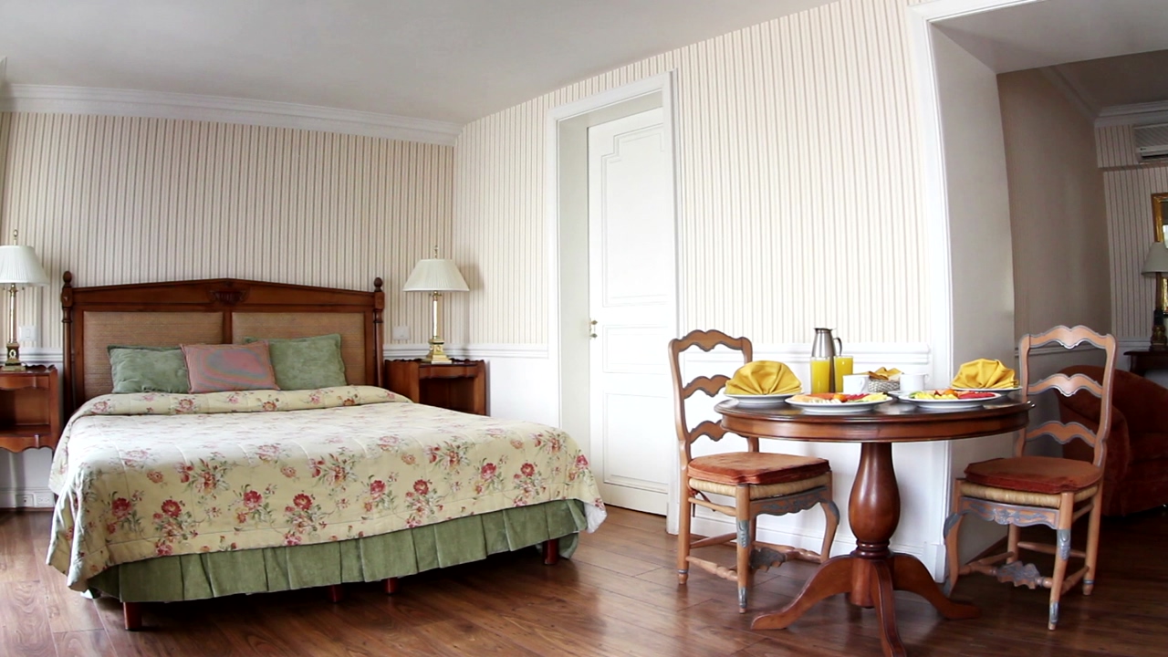 Classic-style hotel room with breakfast served at a table between the bed and sofa