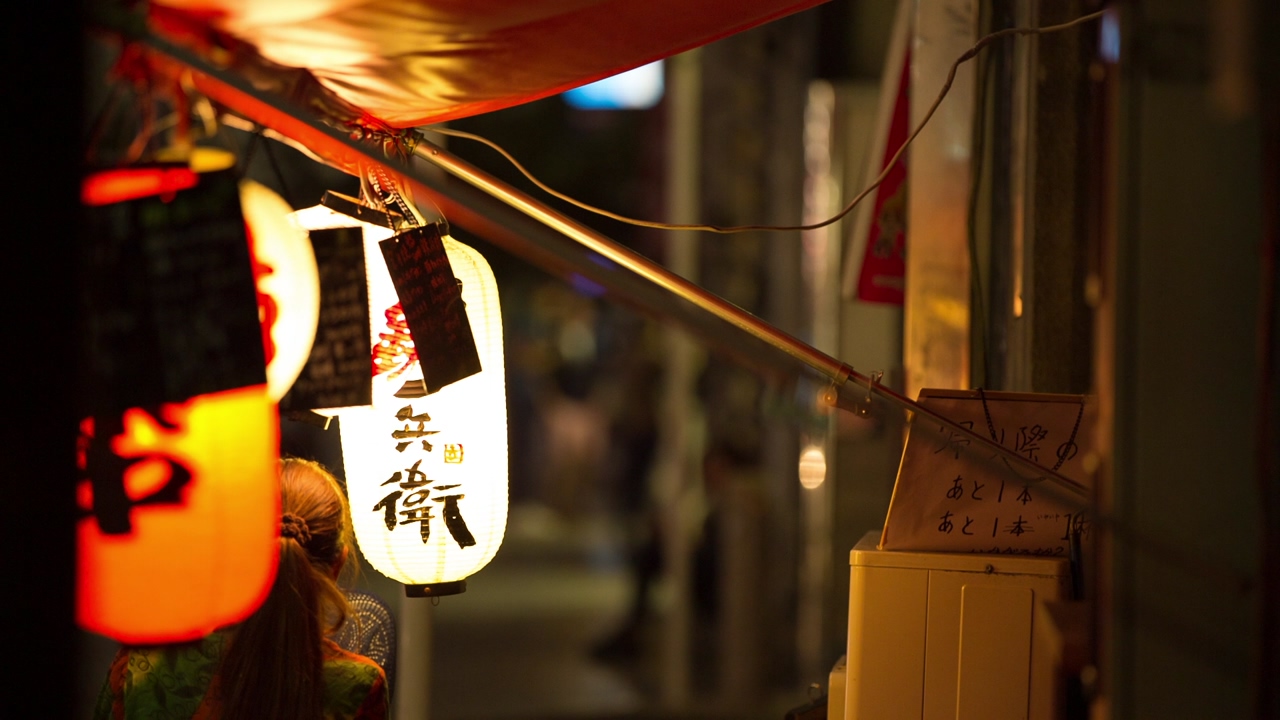 Close up on street paper lamps with chinese characters on them with an unfocused background with people passing by