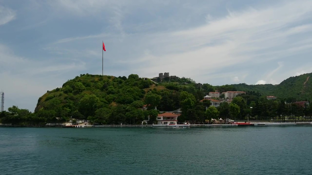 Flag in the top of a coast hill, forest, sea, seashore, coast, houses, and turkey
