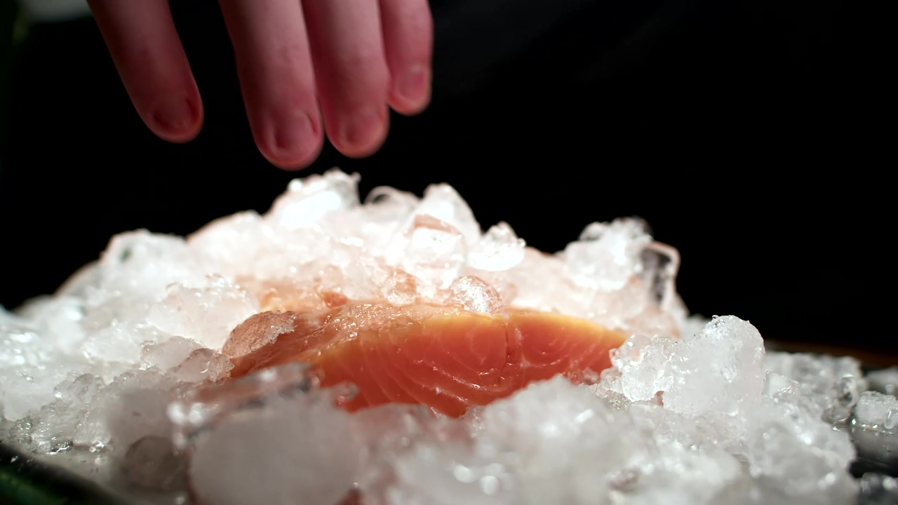 Fresh slice of salmon being picked up from a pile of ice, food preparation, cooking, ice, fish, meal, and seafood