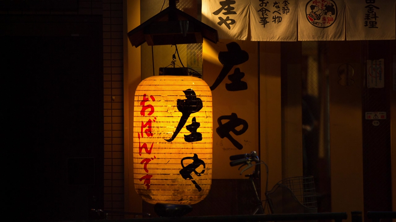 Large paper lamp with japanese characters shines at night on a tokyo city street
