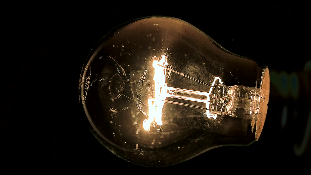 Light globe illuminates on a black background, light, energy, electricity, idea, lamp, globe, and bulb
