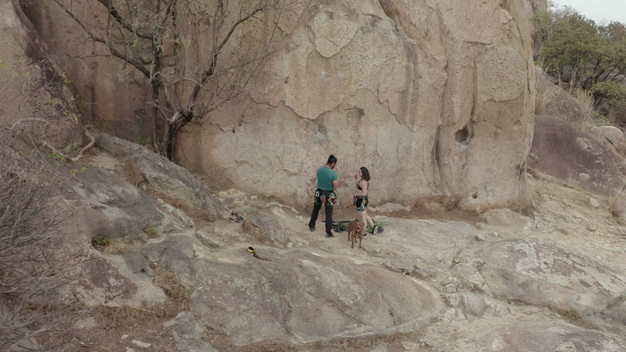 Male and female climbers standing at the base of a rocky mountain, on a day of outdoor climbing in an arid ecosystem