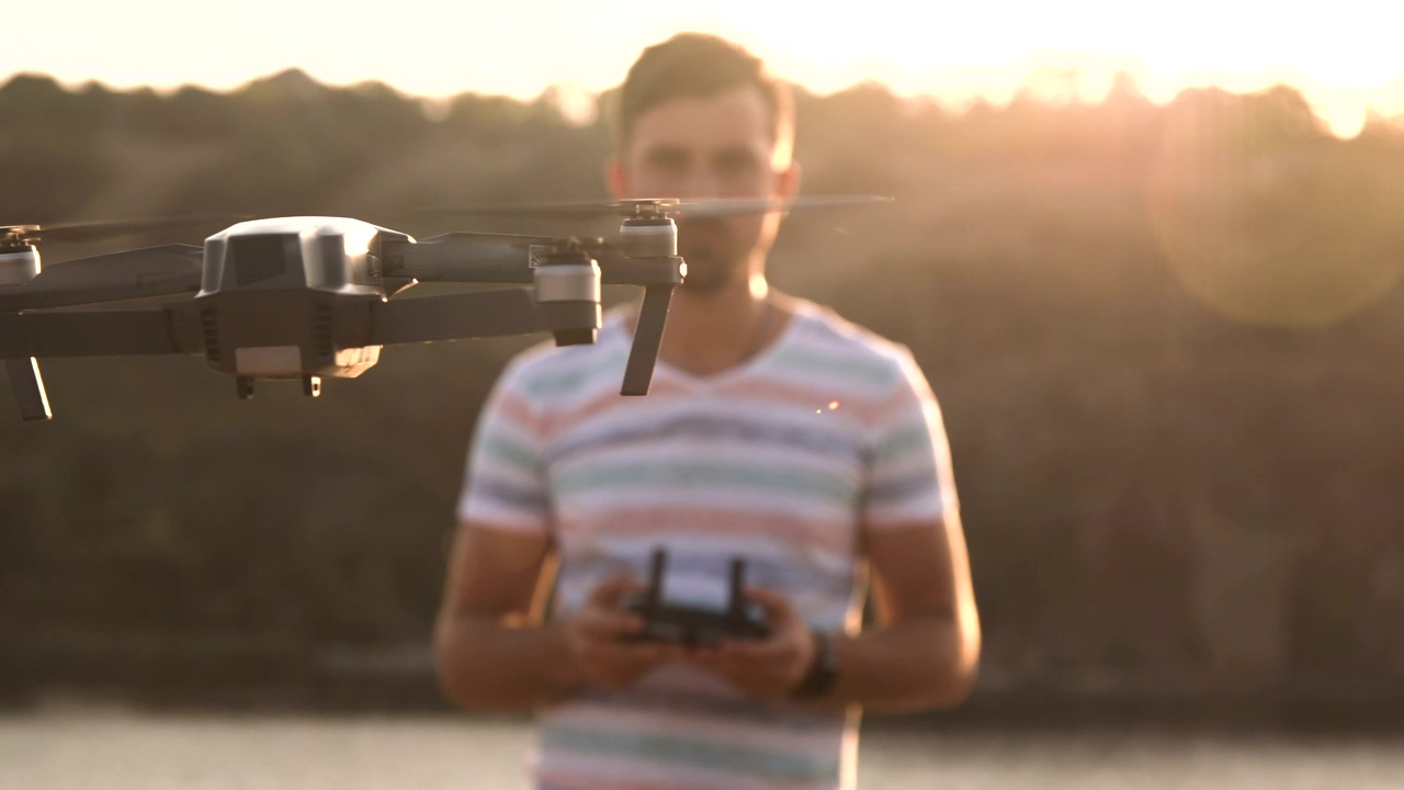 Man controlling drone with with remote controller, outdoor, sunset, technology, device, drone, playing, flying, fly, robot, and drone with