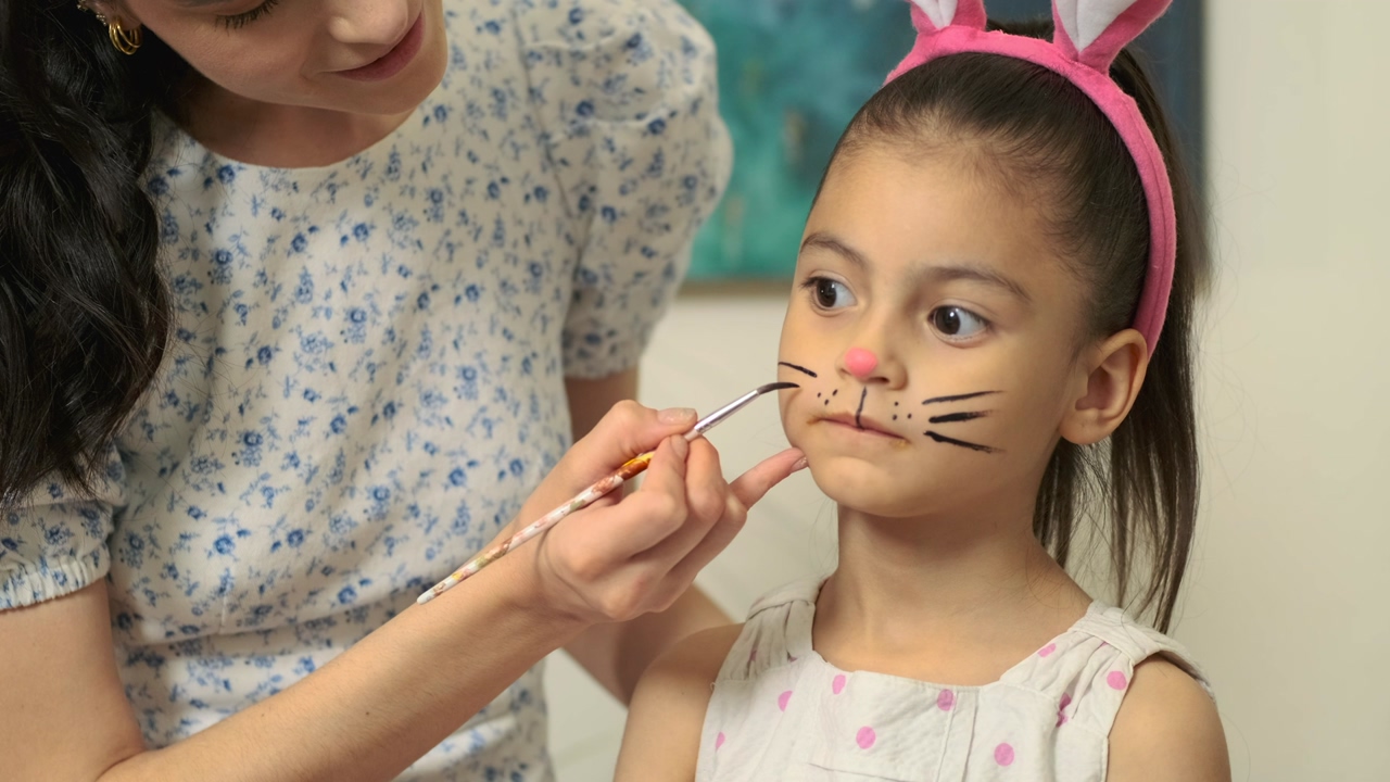 Mother draws mustaches to her daughter while wearing bunny ears to celebrate easter