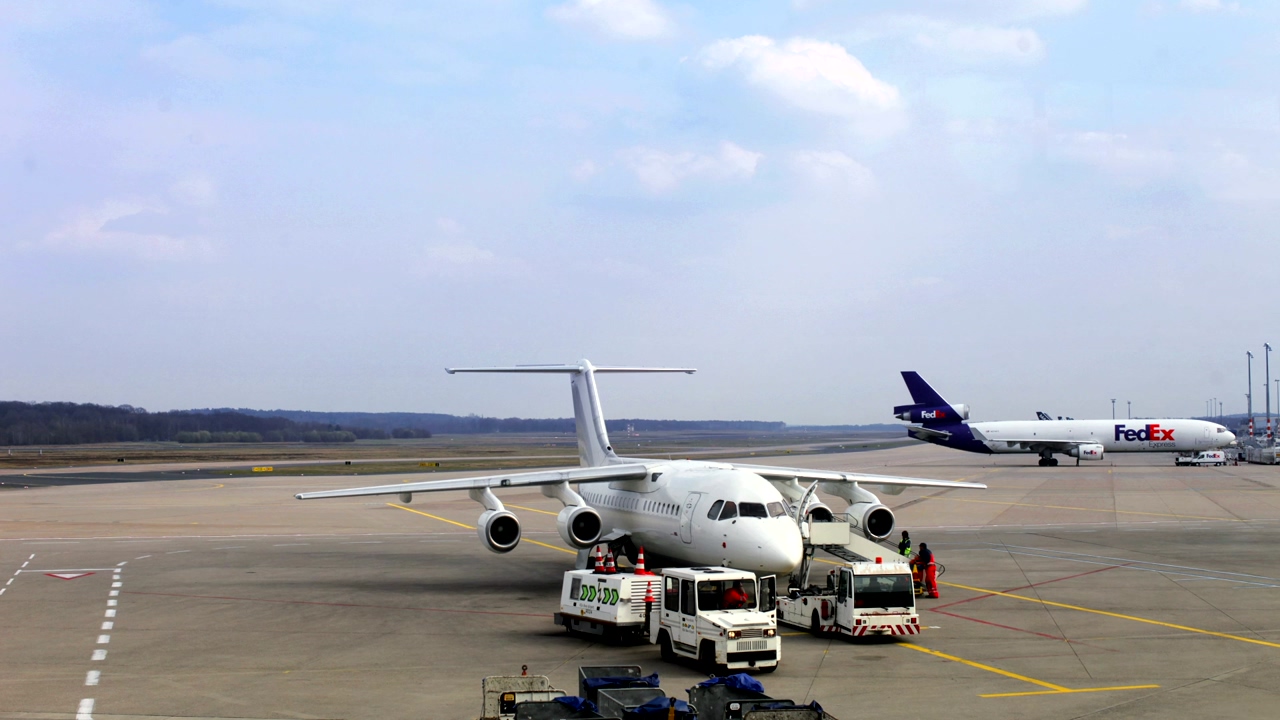 Passenger plane preparing for takeoff near the runway at the airport, airport staff preparing a flight with a fedex transport plane in the background
