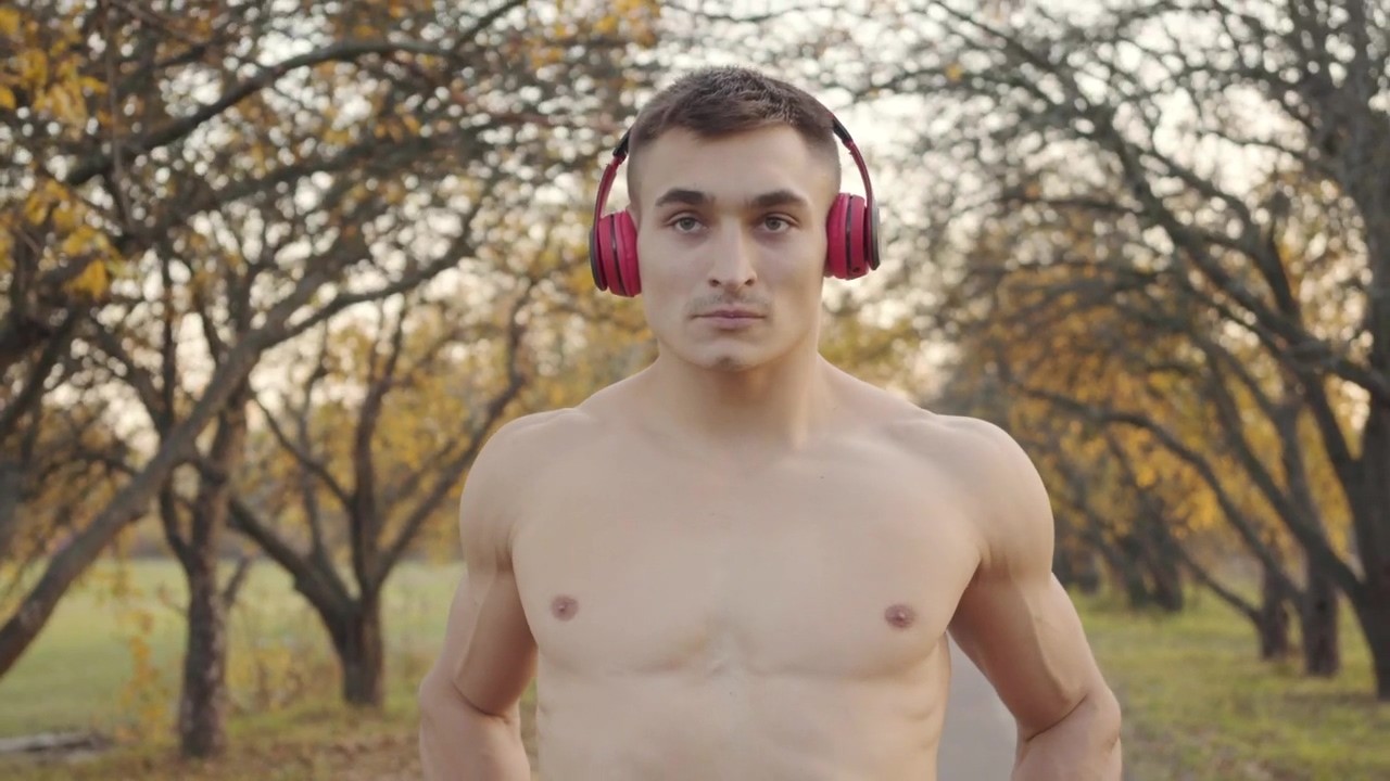 Shirtless man in headphones flexes muscles before outdoor workout, man, outdoor, workout, body care, headphones, body, human body, shirtless, and hamster