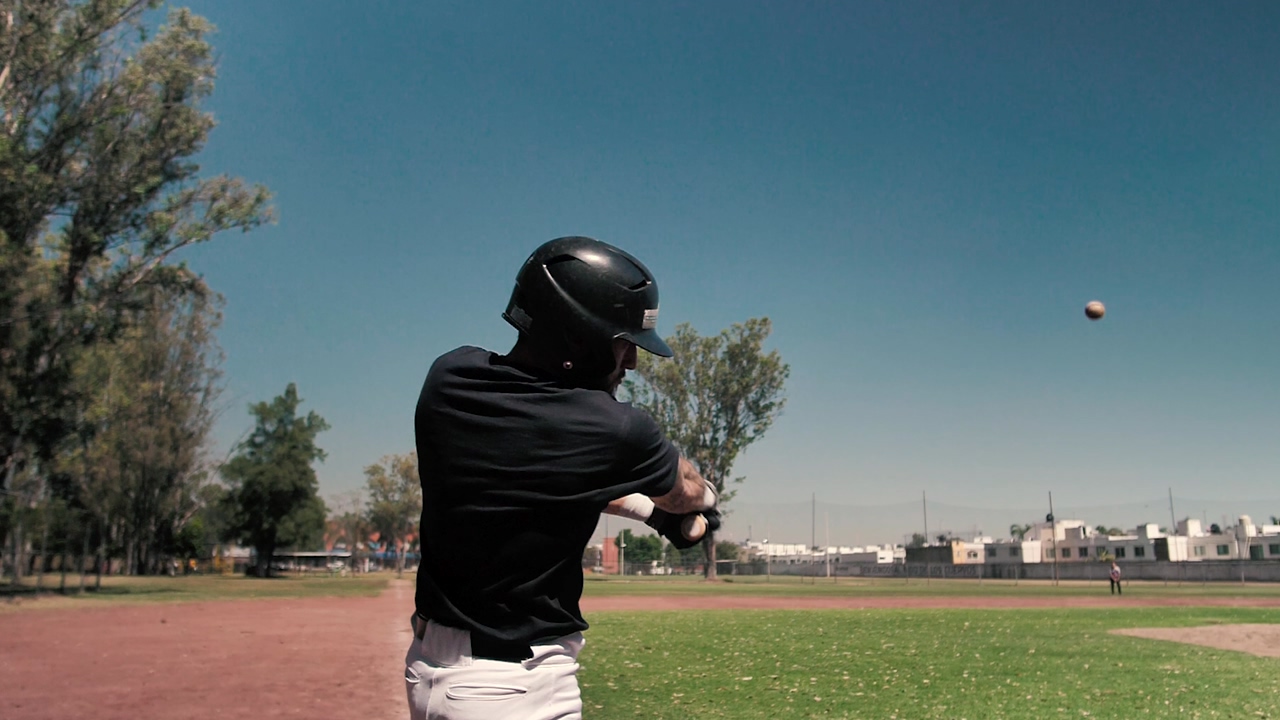 Slow motion video from behind as a baseball batter hits the ball