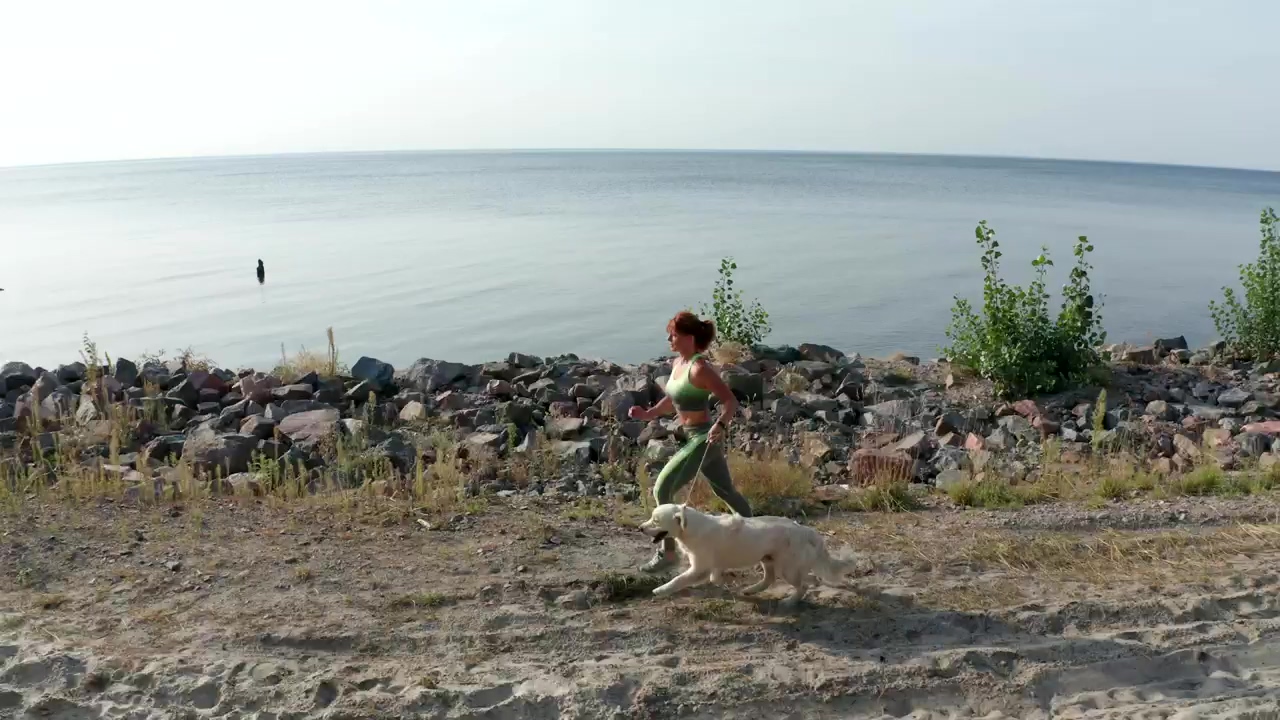 Young woman running with her dog near a coast #dog #runner #walk #pet owner #dog owner